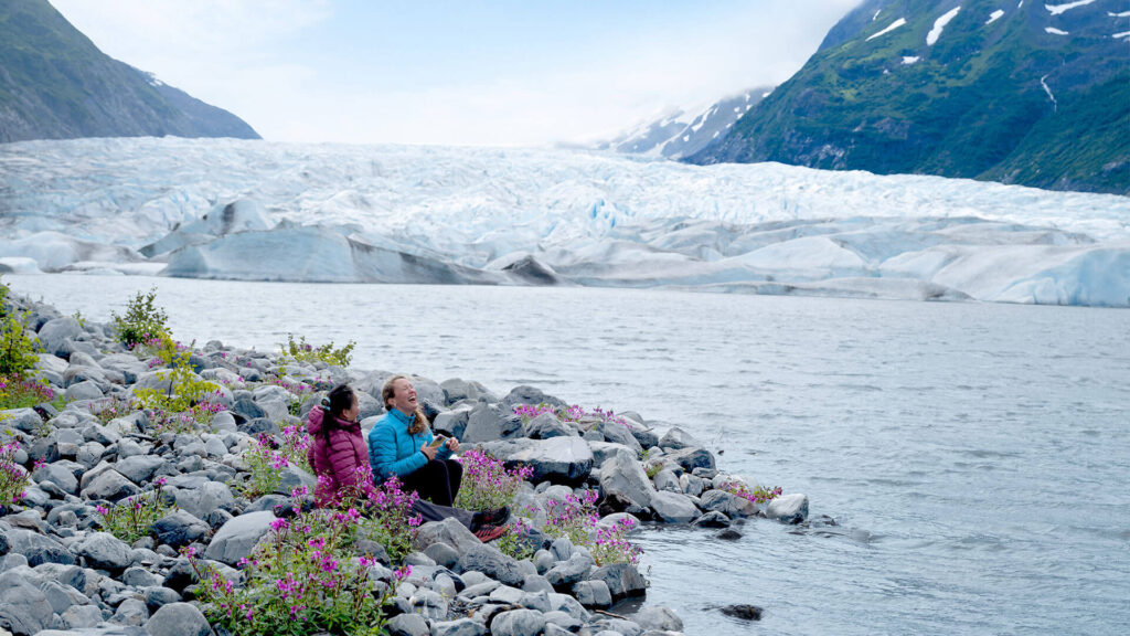 Two people relax on rocks near a river, surrounded by nature and the soothing sound of flowing water.